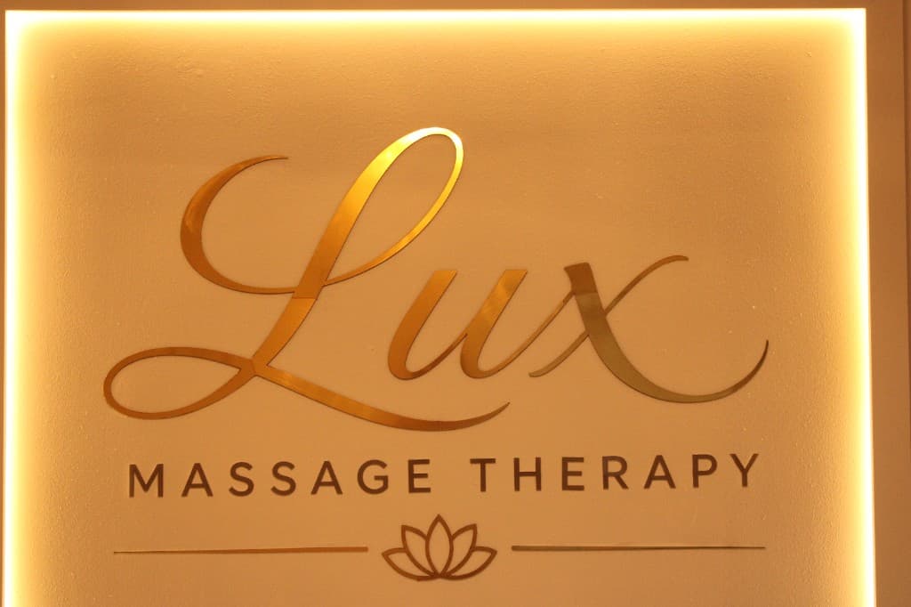 Backlit Lux Massage Therapy gold logo wall at reception